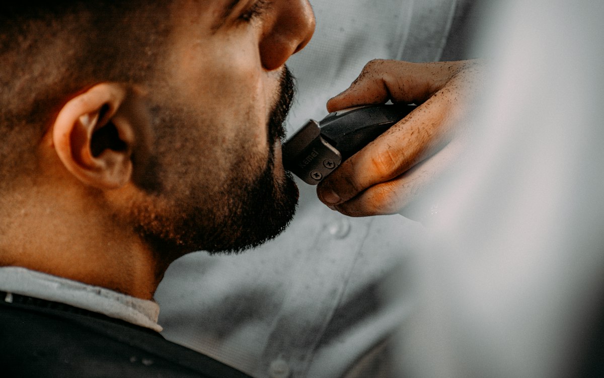 Homem a aparar a barba com um aparador elétrico
