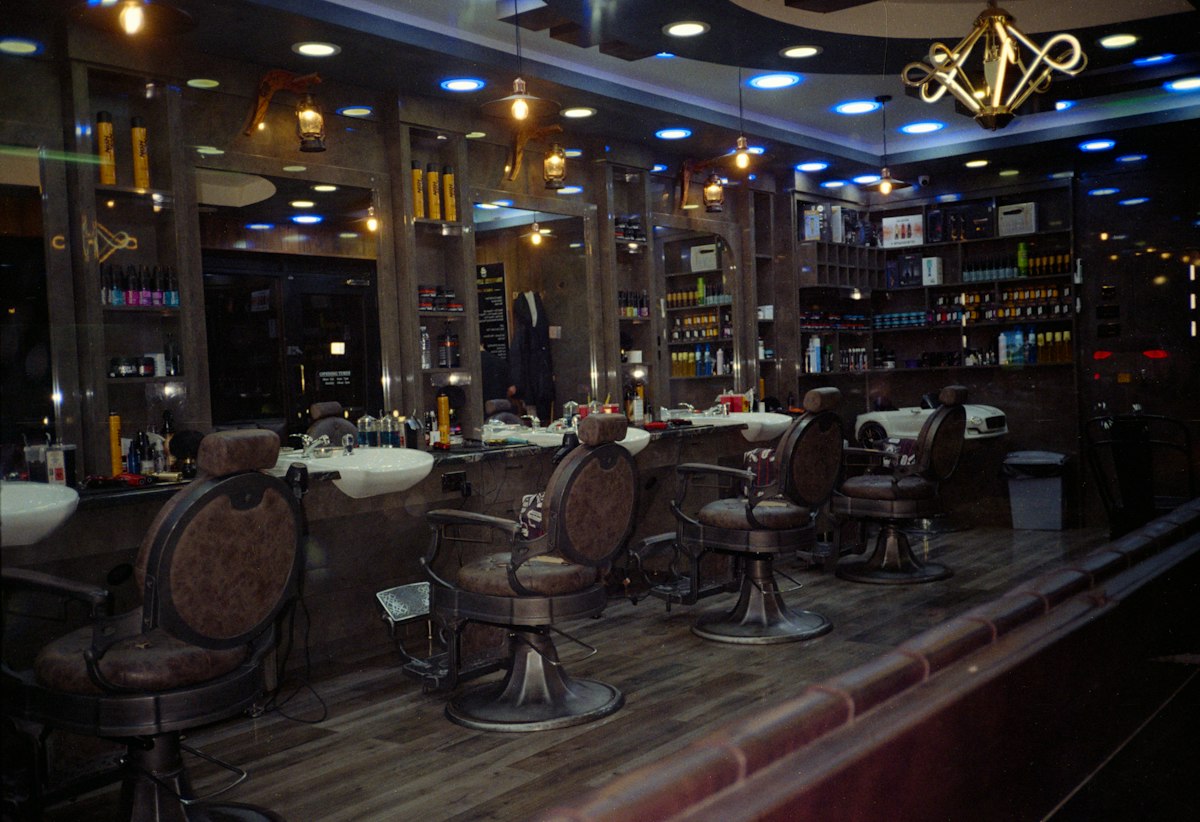 Interior de uma barbearia vazia com cadeiras de barbeiro, espelhos e luz quente