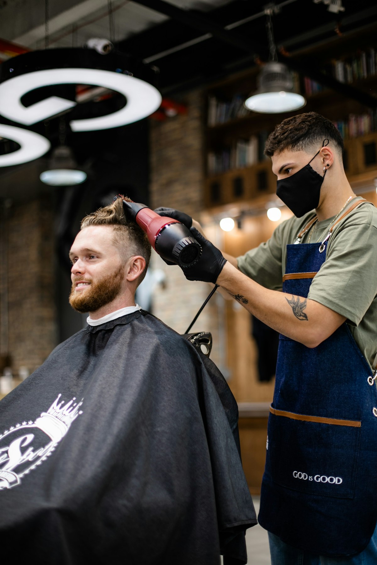 Barbeiro a finalizar o corte de um cliente numa barbearia moderna