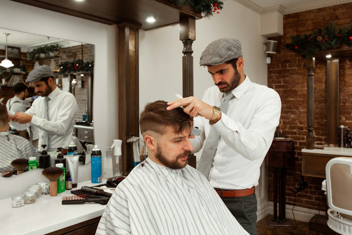 Barbeiro a pentear o cabelo de um cliente numa barbearia
