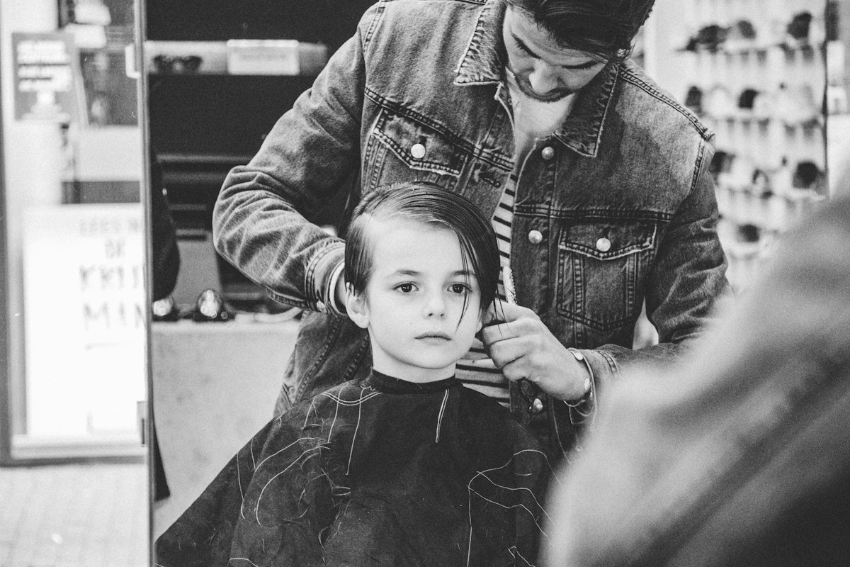Barbeiro a cortar o cabelo a um menino, a preto e branco