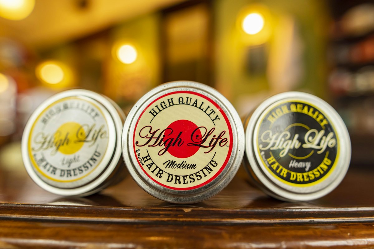 Latas de pomada para o cabelo numa prateleira de barbearia