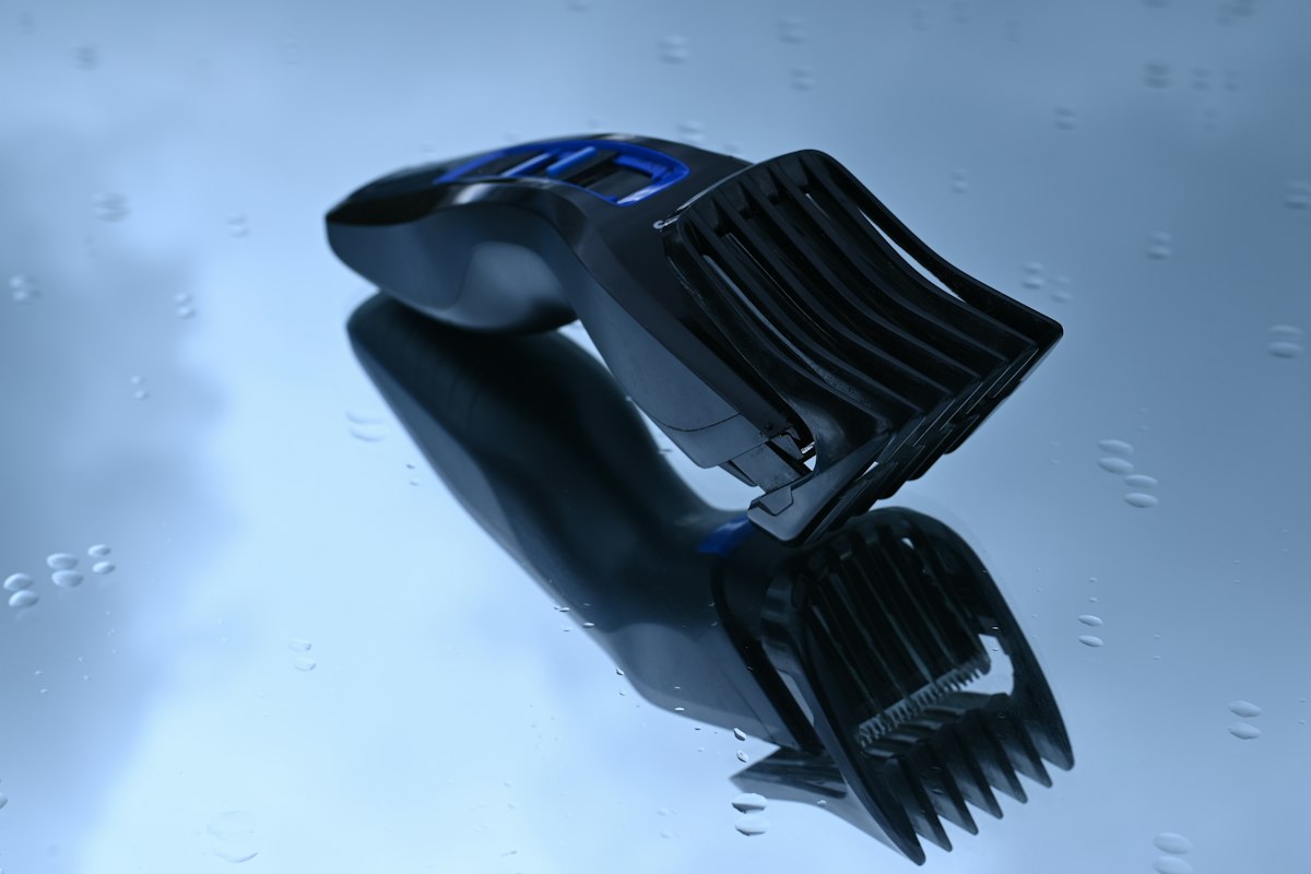 Máquina de cortar cabelo com pente encaixado sobre fundo azul