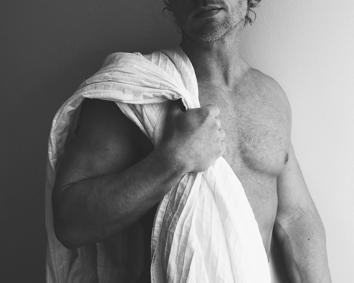 Fotografia a preto e branco de um homem com uma toalha branca ao ombro